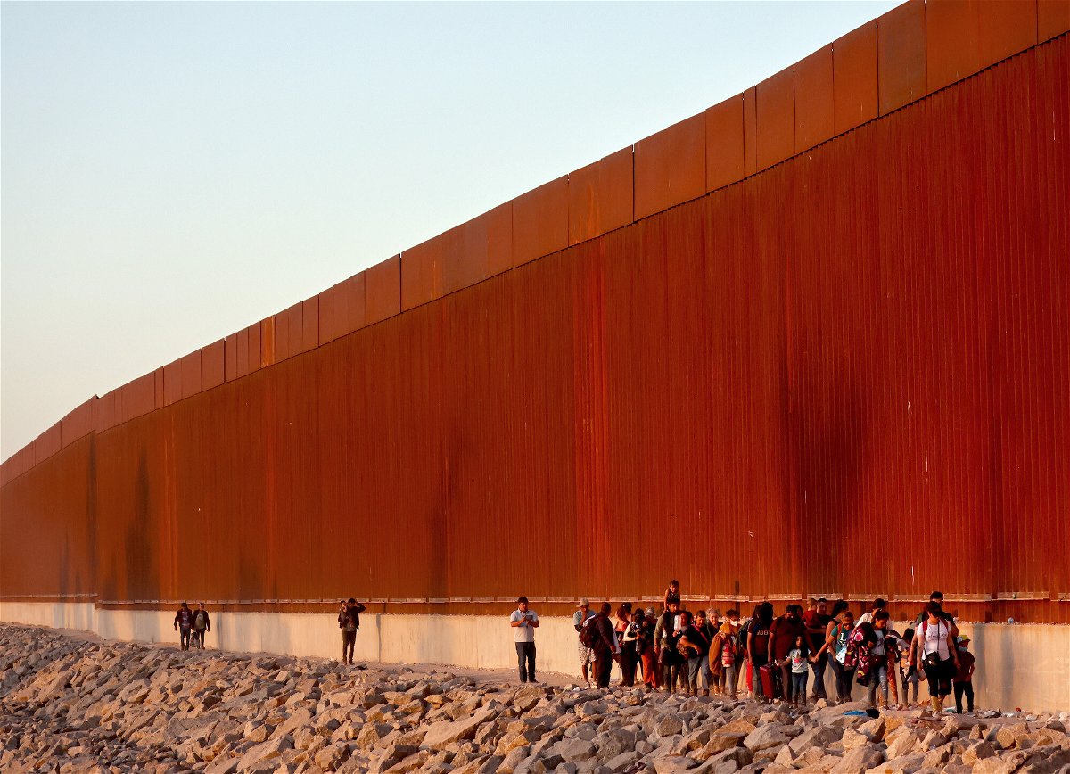 <i>Mario Tama/Getty Images</i><br/>Immigrants walk along the U.S.-Mexico border wall on their way to await processing by the US Border Patrol after crossing from Mexico on May 21