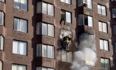 Firefighters rescued a woman dangling from an apartment building in Manhattan where dozens were injured during a fire on Saturday
