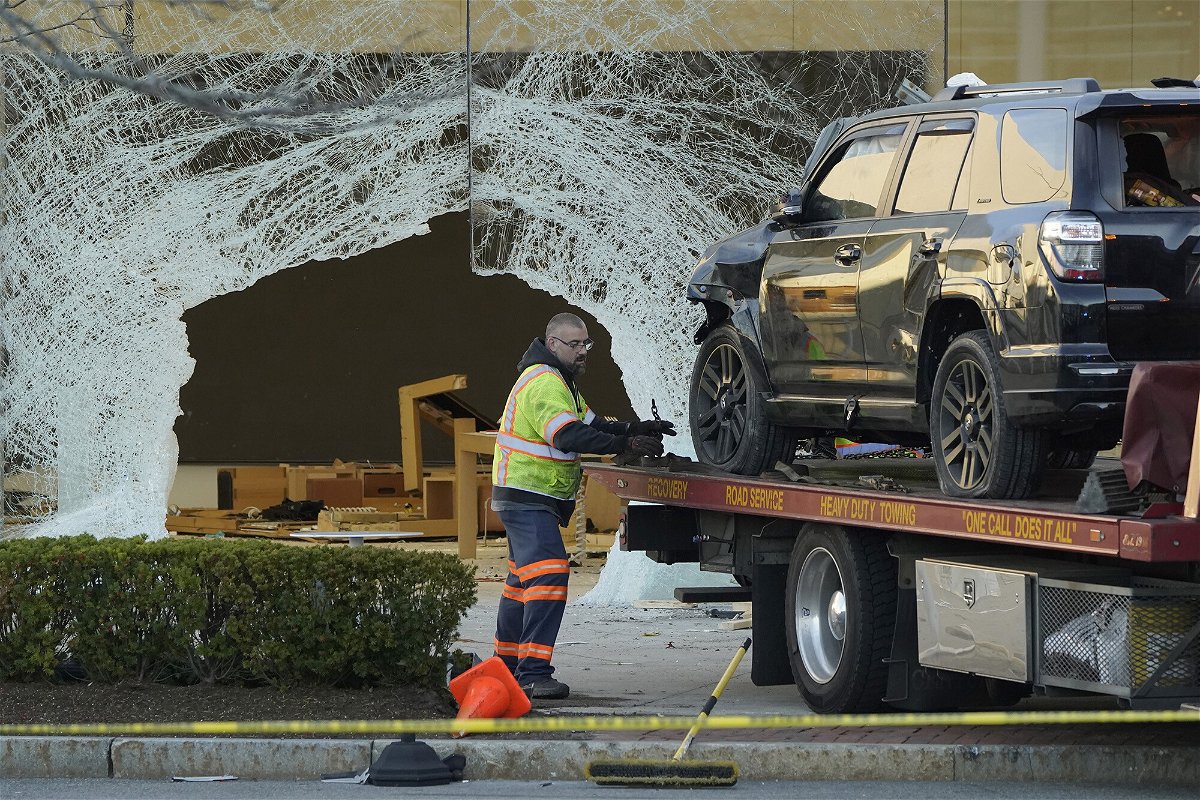 <i>Steven Senne/AP</i><br/>A worker secures a damaged SUV to a flatbed tow truck outside an Apple store