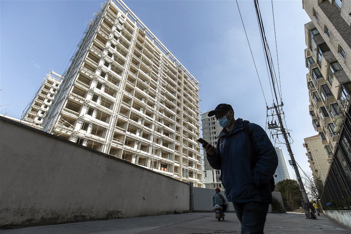 <i>Qilai Shen/Bloomberg/Getty Images</i><br/>A pedestrian passes unfinished apartment buildings at the West Bund Park residential project in Shanghai