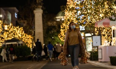 A shopper wearing a face protective mask walks by Christmas decorations at The Grove shopping center in Los Angeles in December 2020.  Leading retailers are sounding the alarm about the danger of a national rail strike.