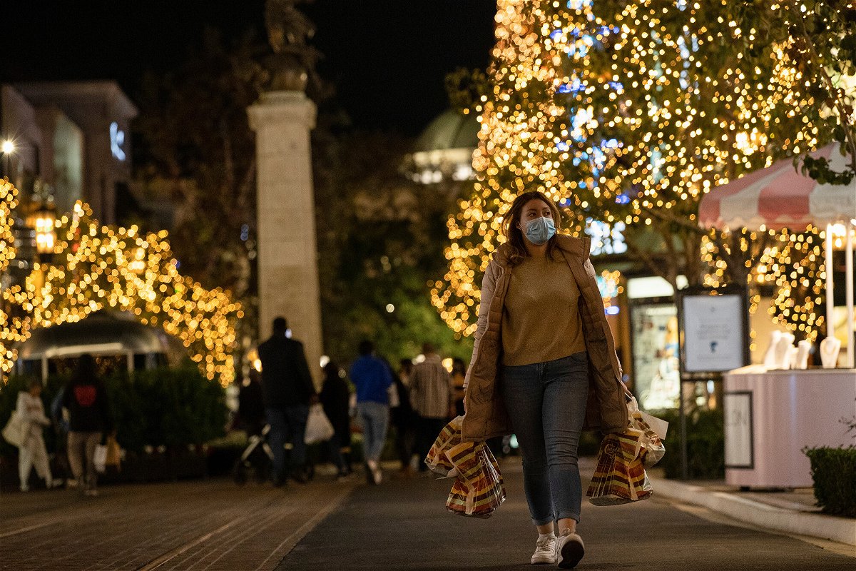 <i>Mario Anzuoni/Reuters</i><br/>A shopper wearing a face protective mask walks by Christmas decorations at The Grove shopping center in Los Angeles in December 2020.  Leading retailers are sounding the alarm about the danger of a national rail strike.