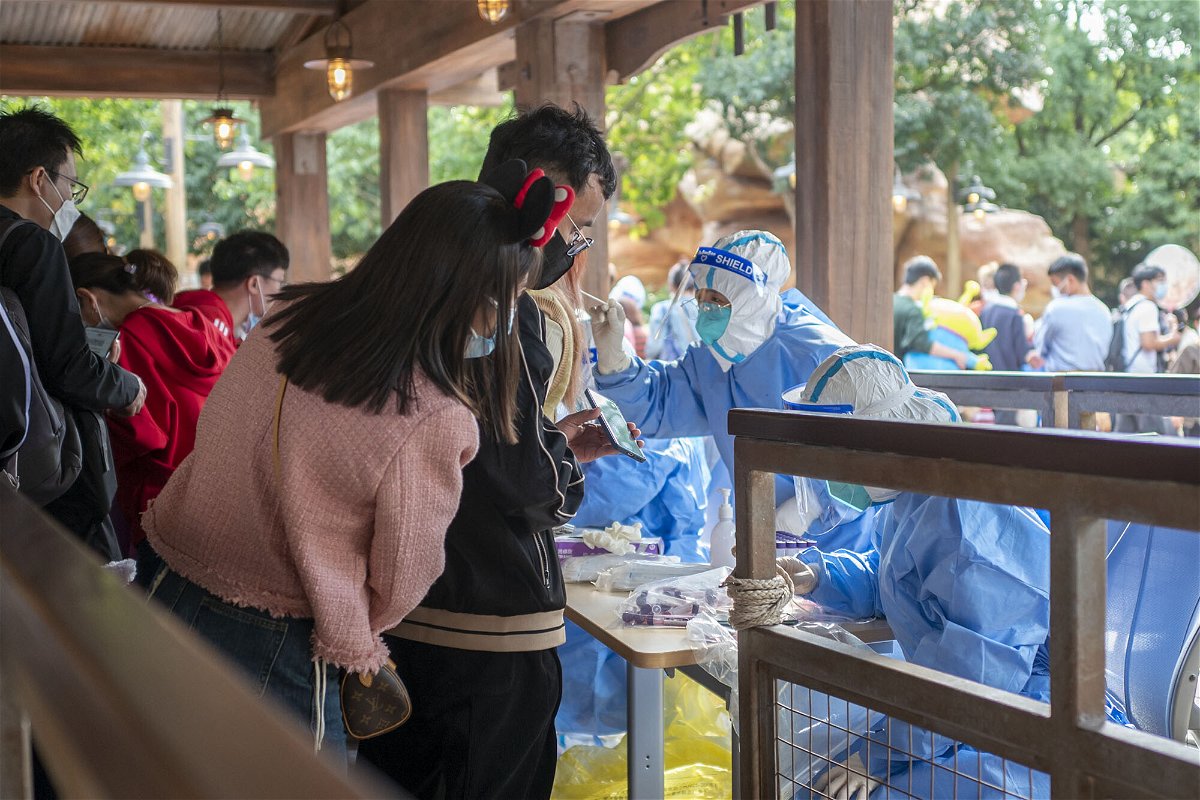 <i>VCG/Getty Images</i><br/>China's Covid-19 curbs are again hurting business. Medical workers here carry out Covid-19 testing on tourists at Shanghai Disney Resort on October 31