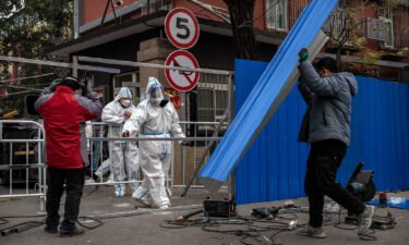 Epidemic control workers wear protective suits as they help workers erect a metal barrier fence outside a community under lockdown to prevent the spread of Covid-19 on November 24