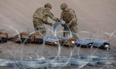 Texas National Guard troops unroll coils of concertina wire Wednesday near the US-Mexican near Ciudad Juarez.