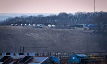 A line of vehicles parked near the rural Iowa site where authorities were searching for human remains said to have been buried there by a serial killer.