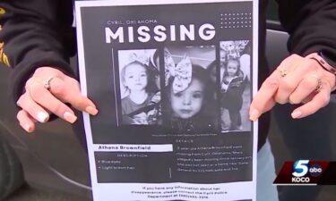 A woman holds up the missing poster for Athena Brownfield