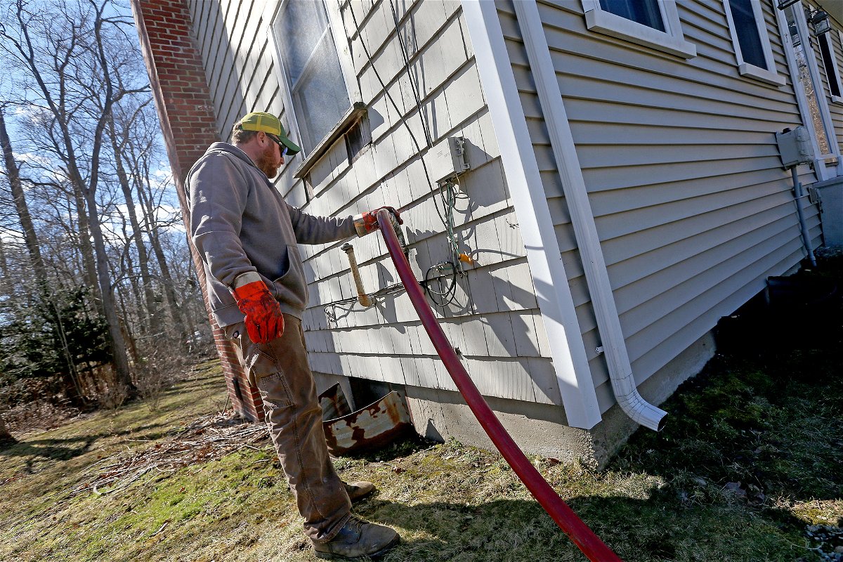 <i>Matt Stone/MediaNews Group/Boston Herald/Getty Images</i><br/>Corey Carlson of Anderson Fuel fills a house with home heating oil which has risen to over $5.00 a gallon on March 8