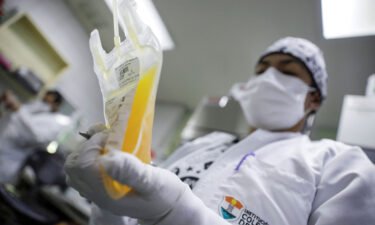 A laboratory technician holds a bag of convalescent plasma