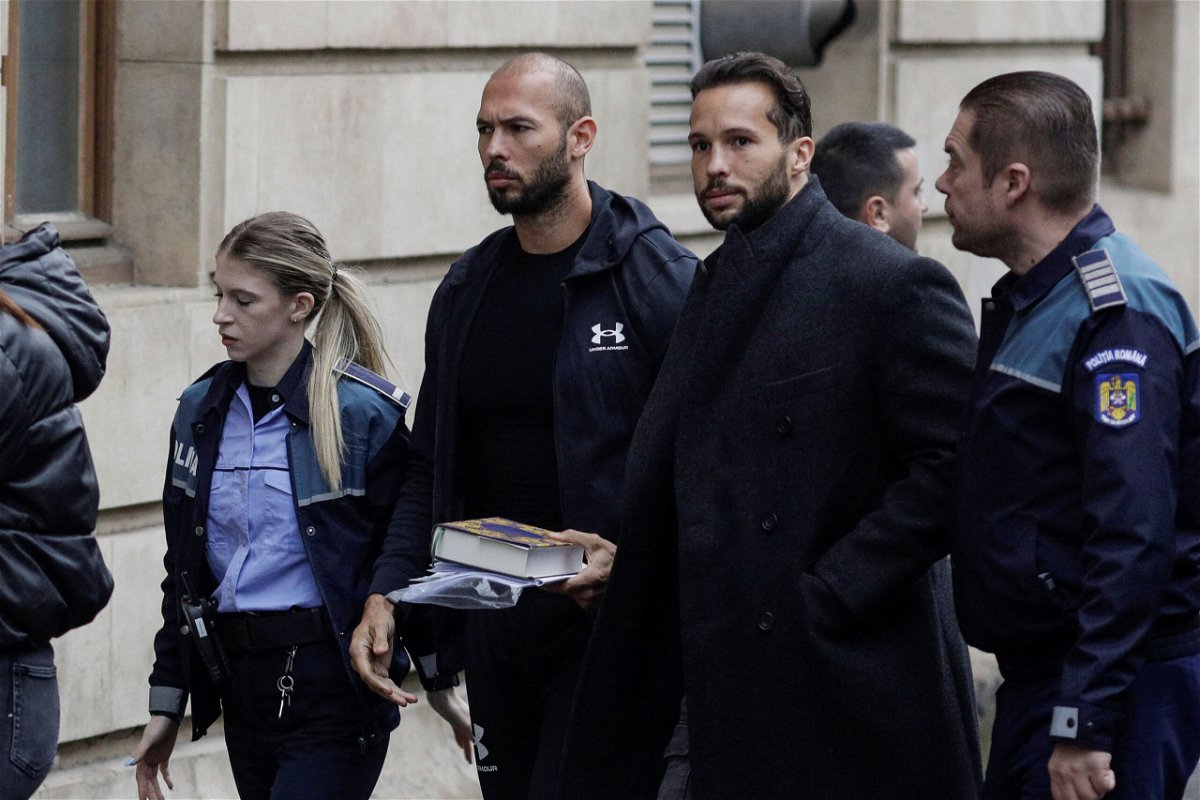 <i>Octav Ganea/Inquam Photos/Reuters</i><br/>Andrew Tate (left) and his brother Tristan are escorted by police officers outside the headquarters of the Bucharest Court of Appeal
