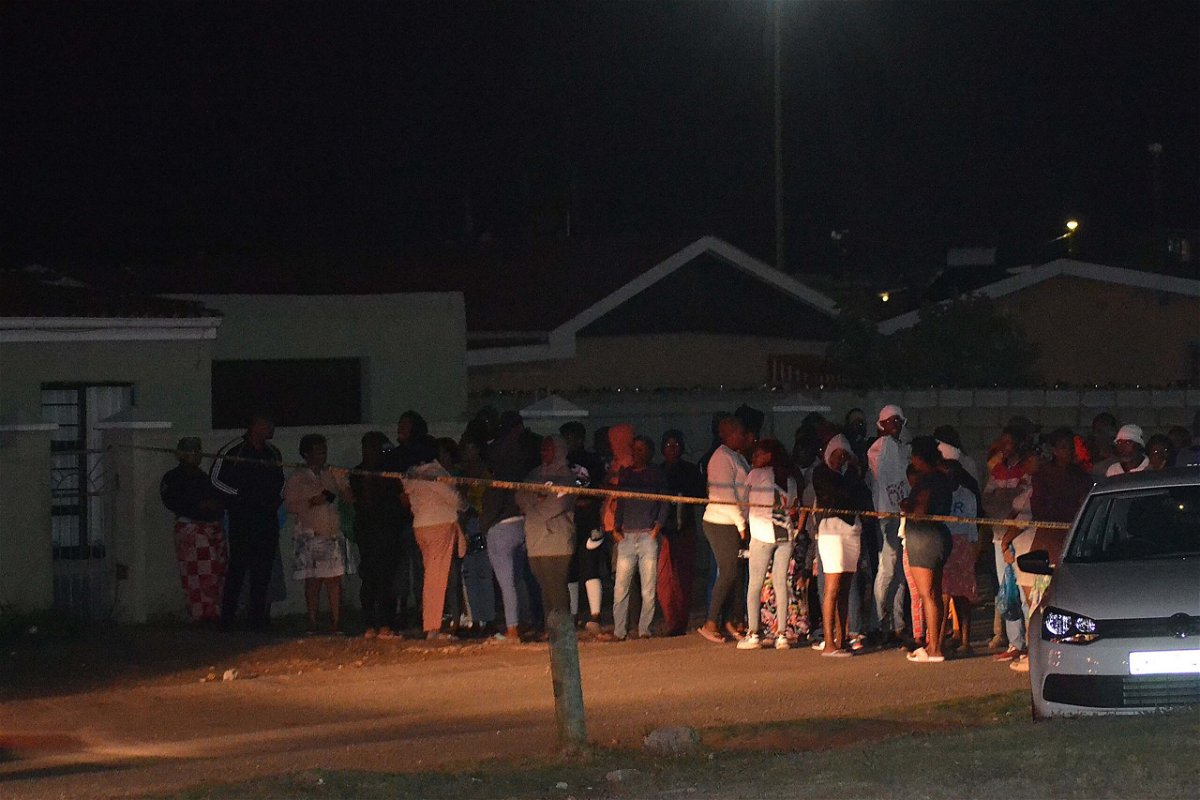 <i>LUVUYO MEHLWANA/AFP/Getty Images</i><br/>Bystanders wait behind a police tape marking the scene of a mass shooting in Gqeberha
