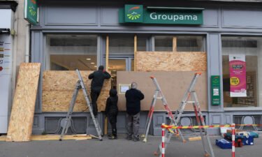 Workers board up the windows of an insurance group branch located on the route of a demonstration