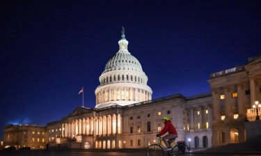 A bicyclist rides past the US Capitol at dusk as the House meets to vote on a rules package for the 118th Congress