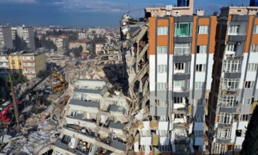 Cranes remove debris next to destroyed buildings in Antakya