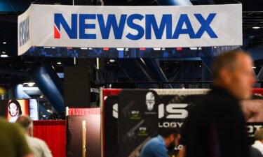 Signage for the Newsmax conservative television broadcasting network is displayed at a broadcast TV booth at the National Rifle Association (NRA) annual meeting at the George R. Brown Convention Center