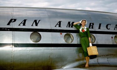 A model poses as a passenger walking off the Pan American Clipper "Challenge" Lockheed 1049 airliner circa 1947.