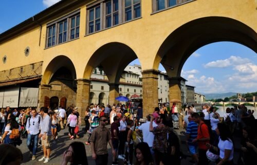 People walk on the Ponte Vecchio onto Arno river