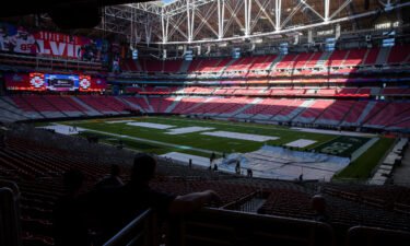 Workers cover the field with a tarp ahead of a rehearsal for the Super Bowl LVII Halftime Show at State Farm Stadium in Glendale