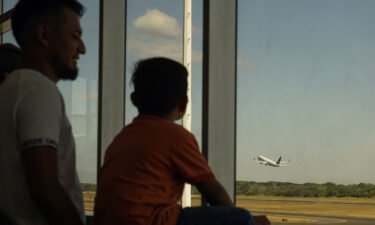A man and his son watch a United Airlines plane take off from Comalapa International Airport on February 18 in La Paz