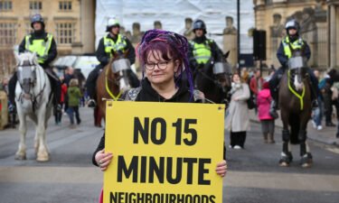 A woman holds a placard at a protest against 15-minute cities in Oxford