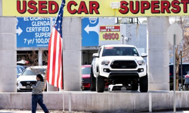 A pedestrian walks past a used car lot on February 15 in Glendale