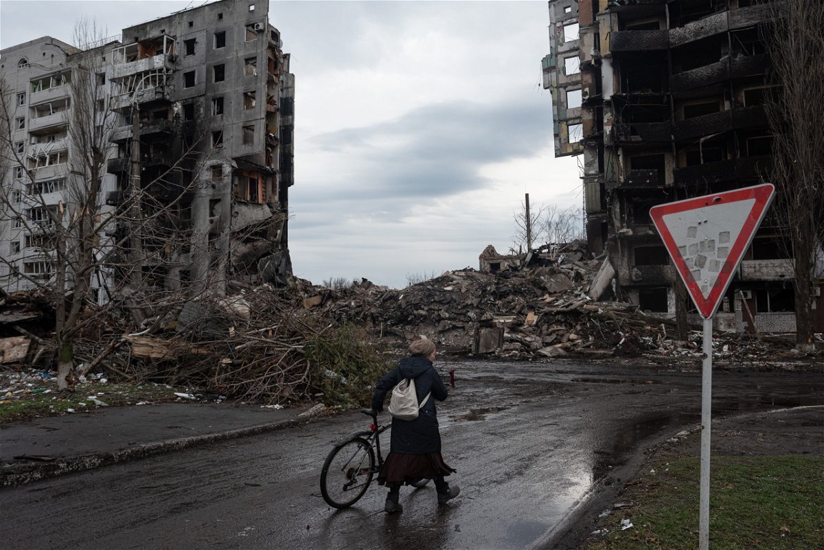 <i>Alexey Furman/Getty Images</i><br/>A woman pushes her bicycle in front of a destroyed apartment building in Borodianka
