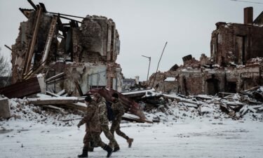 Ukrainian servicemen walk past a destroyed building in Kupiansk