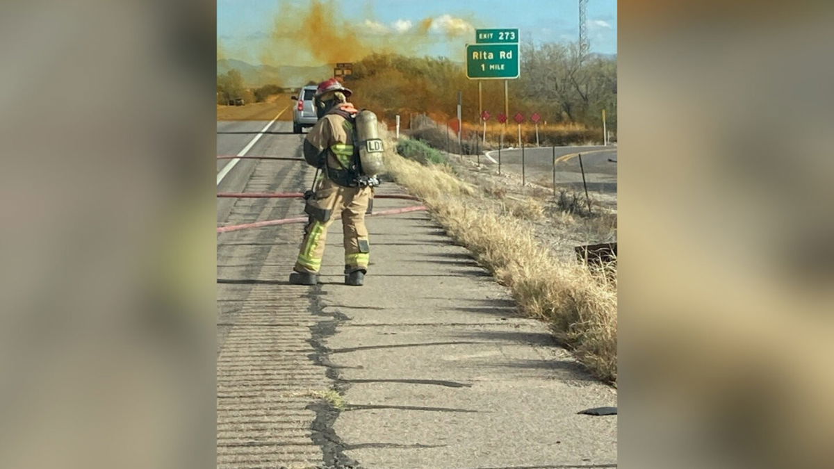 <i>Tucson Fire Service/Reuters</i><br/>A firefighter works as an overturned truck spews orange smoke in the background on Interstate 10 in Tucson