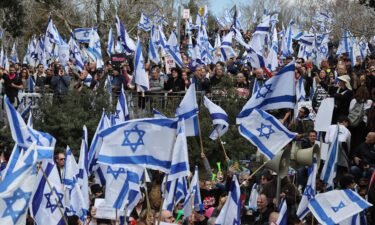 Israeli protesters lift national flags and placards as they rally outside the Knesset in Jerusalem on Monday.