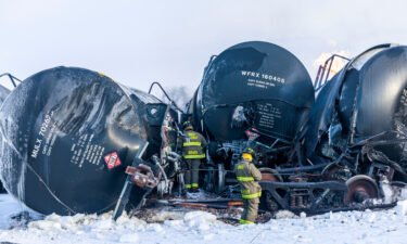 Firefighters work near piled up train cars