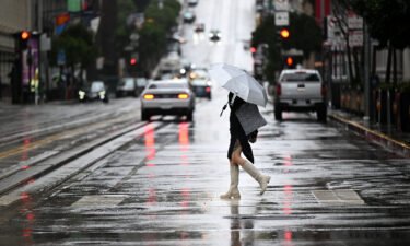 People walk with umbrellas on California Street during a rainy day in San Francisco Tuesday.