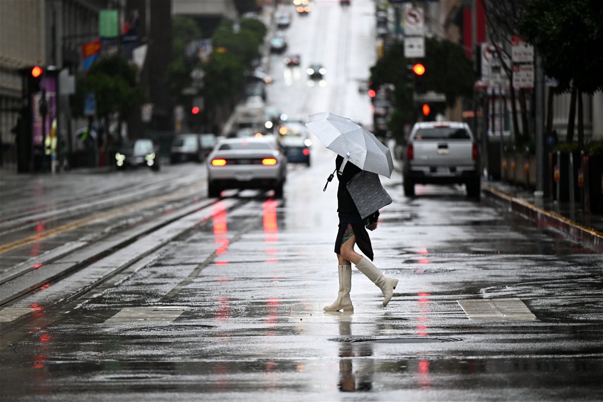 <i>Tayfun Coskun/Anadolu Agency/Getty Images</i><br/>People walk with umbrellas on California Street during a rainy day in San Francisco Tuesday.