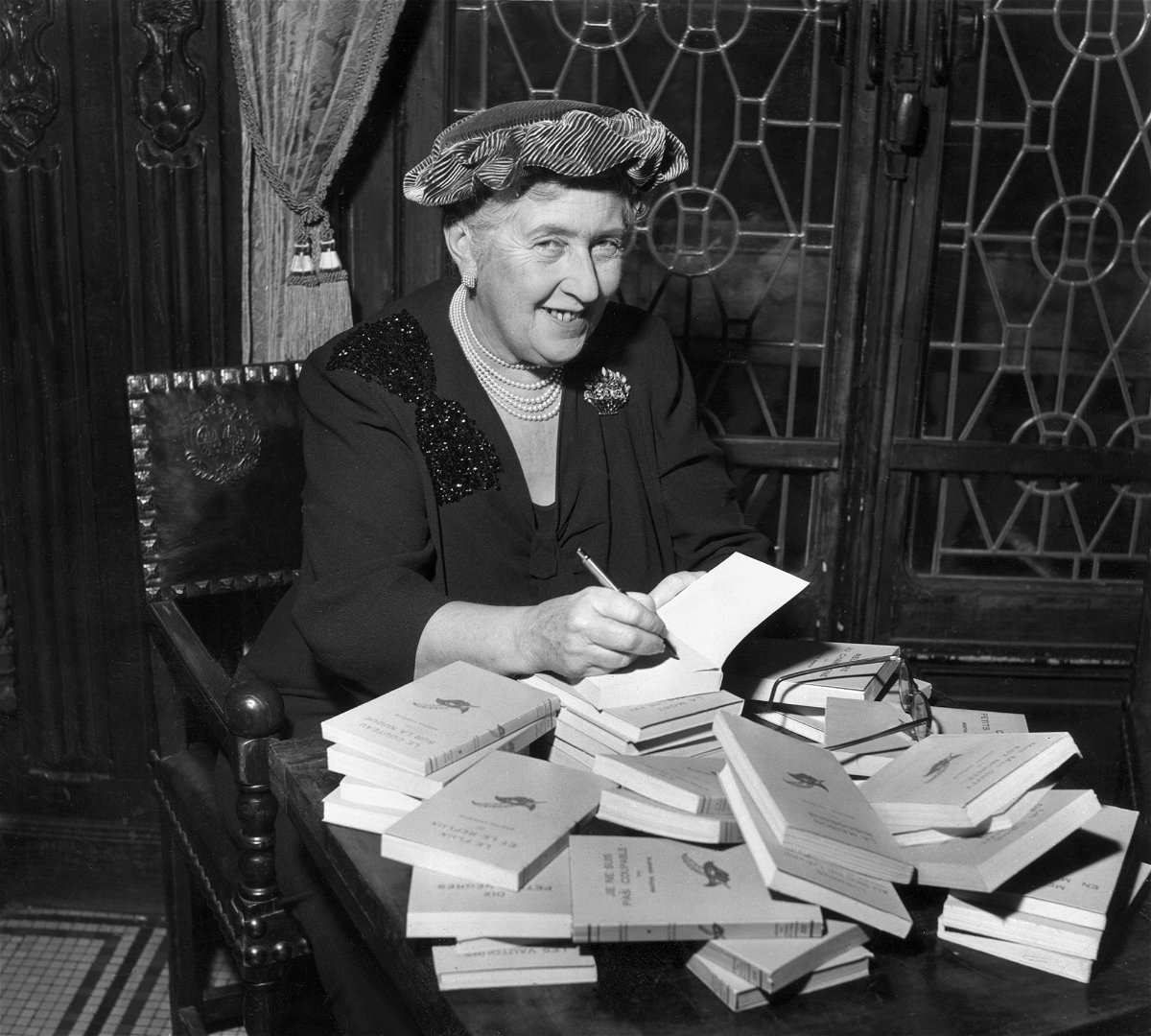 <i>Hulton Archive/Getty Images</i><br/>Agatha Christie signs copies of her books in around 1950. Her works are revised to remove racist references and other language considered offensive to modern audiences.