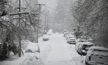 A vehicle attempts to drive along snow-covered Conaway Avenue in Grass Valley