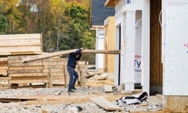 The US economy grew at a slower pace in the fourth quarter than previously estimated. A man carries siding into a house at a new home construction site in Trappe