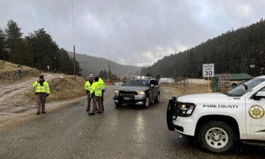 Sheriff deputies block a road in a Colorado town where authorities found an abandoned car that belonged to the suspect in a shooting of two administrators at a Denver high school Wednesday.