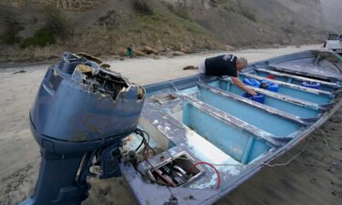 Boat salvager Robert Butler picks up a canister in one of the two boats sitting on Blacks Beach on March 12