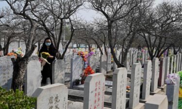 Beijing's population has declined for the first time in 19 years. A woman carries flowers as she visits the Babaoshan People's Cemetery in Beijing
