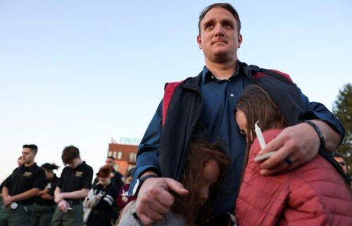 R.T. VanOrden shields his daughters from the wind during a vigil for the victims of a deadly shooting at the Covenant School in Nashville