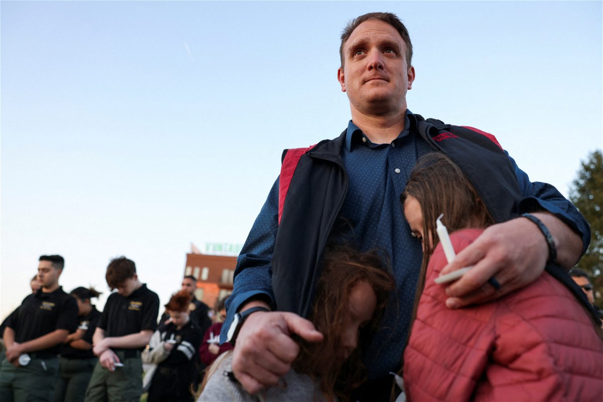 <i>Austin Anthony/Reuters</i><br/>R.T. VanOrden shields his daughters from the wind during a vigil for the victims of a deadly shooting at the Covenant School in Nashville