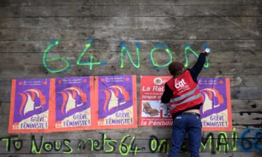 An anti-pension reform demonstrator writes "64-non" on part of a roadblock to the oil terminals at the Total Energies refinery during a protest in Donges