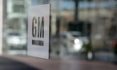 General Motors is cutting hundreds of white collar jobs to remain competitive in the shift to electric vehicles. GM signage is displayed outside the company's headquarters in Detroit