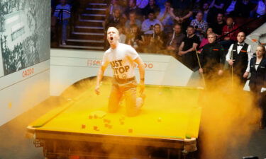 A Just Stop Oil protester jumps on the table and throws orange powder paint during a match.