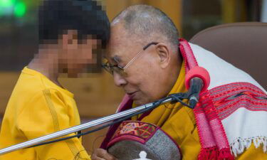 Tibetan spiritual leader the Dalai Lama touches foreheads with a young boy