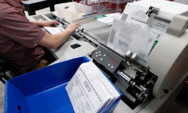 An election worker opens envelopes and removes ballots so they can be counted at the election office on October 26