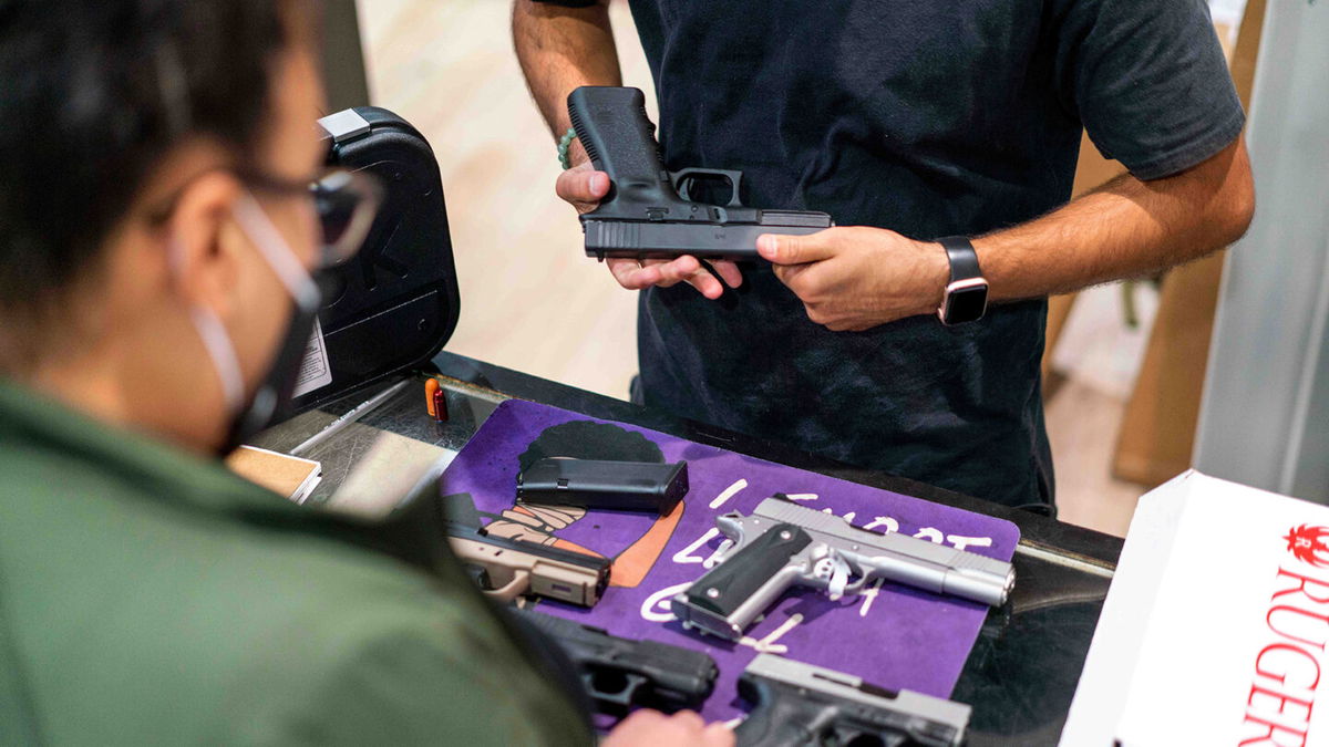 <i>Kyle Grillot/Bloomberg/Getty Images</i><br/>An employee shows a customer a Glock 17 pistol for sale at Redstone Firearms