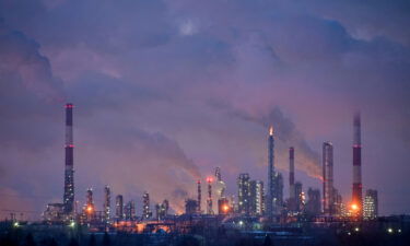 Flue gas and steam rise out of chimneys and smokestacks of an oil refinery during sunset on a frosty day in the Siberian city of Omsk