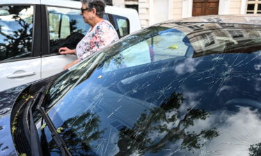 A woman walks past a car hit by a hailstorm in southeastern France.