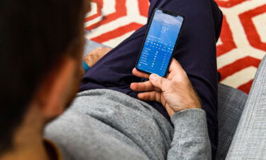 A man using an Apple iPhone Xs looks at the weather application in Paris