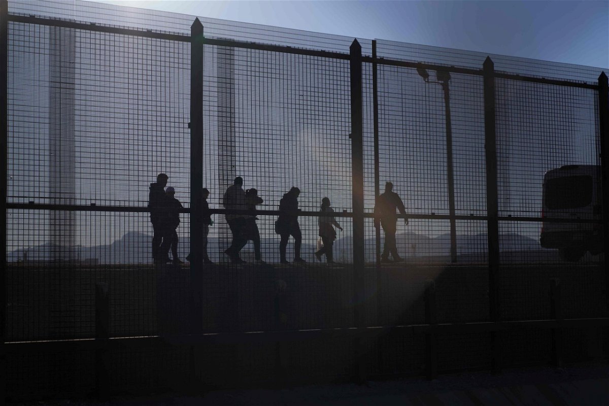 <i>Allison Dinner/AFP/Getty Images</i><br/>A US Border Patrol agent leads migrants who crossed into the US from Mexico to a van for transportation in El Paso